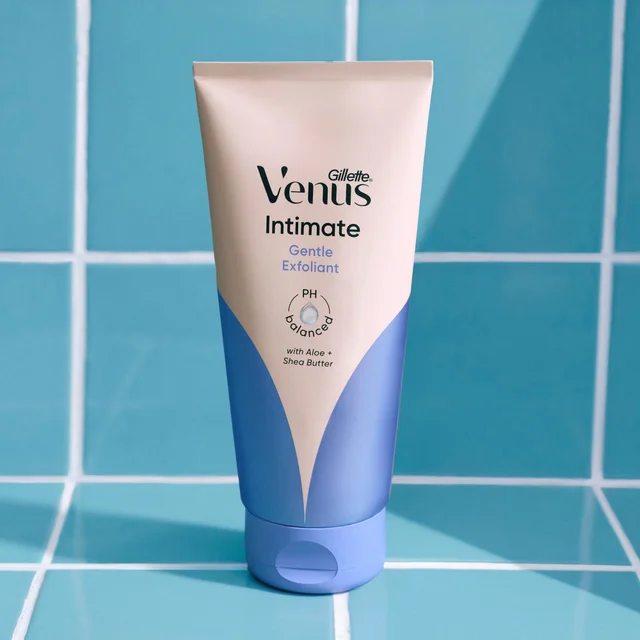 Gillette Venus Intimate Gentle Exfoliant for pubic hair and skin to help prevent ingrowns, pH Balanced, with Aloe and Shea Butter, in a blue tube against a background of blue square tiles.