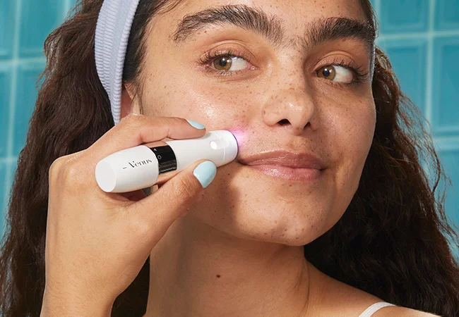 Woman using mini hair remover on the face